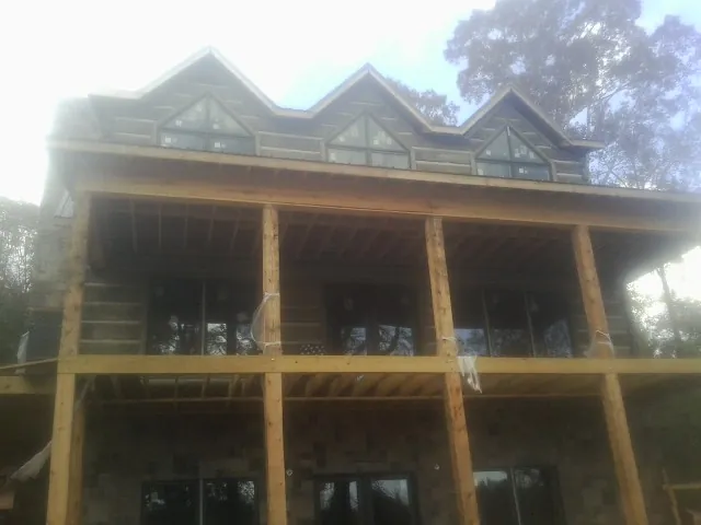 Dormers and porch framing on a large log home under construction — Roof Coating work by our crew in Torrington