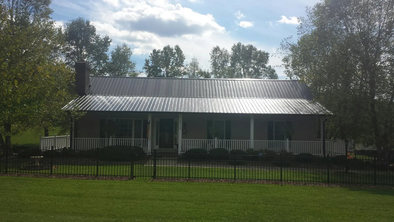 Gray metal roof on a brick ranch with a full width front porch — Gutter Guard Installation work by our crew in Torrington