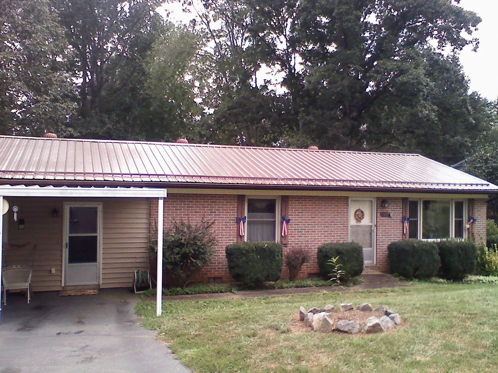 Bronze metal roof and carport on a brick ranch home — Roof Repair work by our crew in Torrington